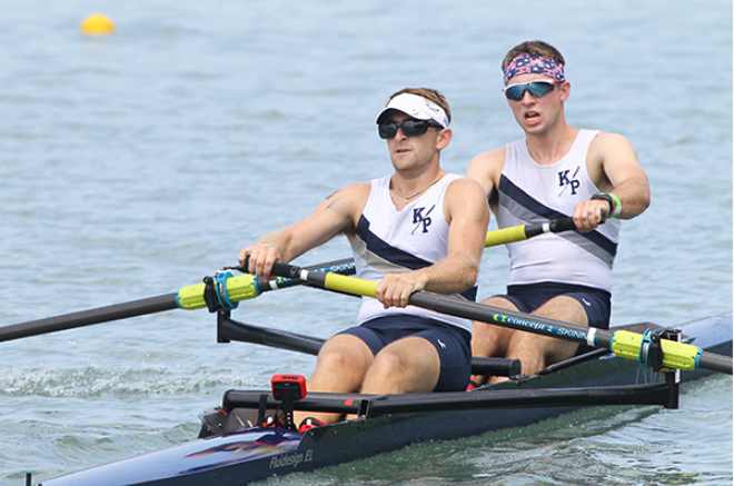 Two young men rowing in white Kings Point shirts.