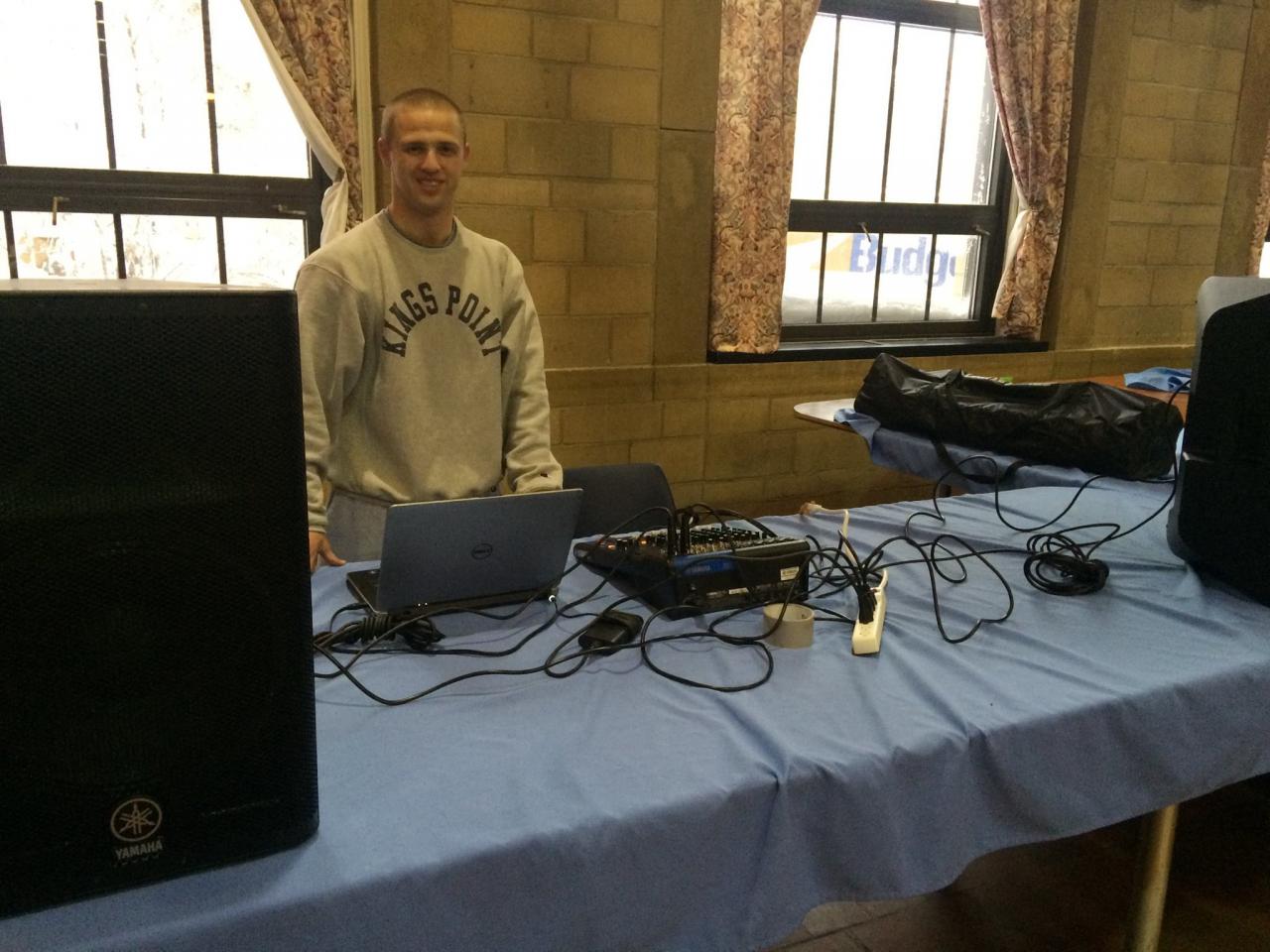A student stands behind a desk.