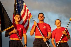 Midshipman leadership running with Battle Standard and US Flag